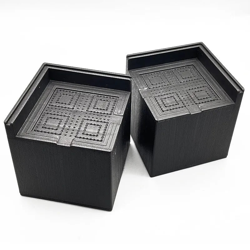 Four black plastic bed foot mats for furniture height adjustment and leg stabilisation