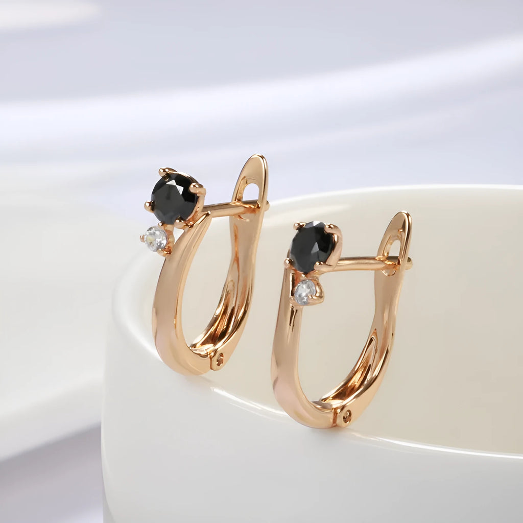 Gold geometric drop earrings with black agate stone inlay on a model's ear