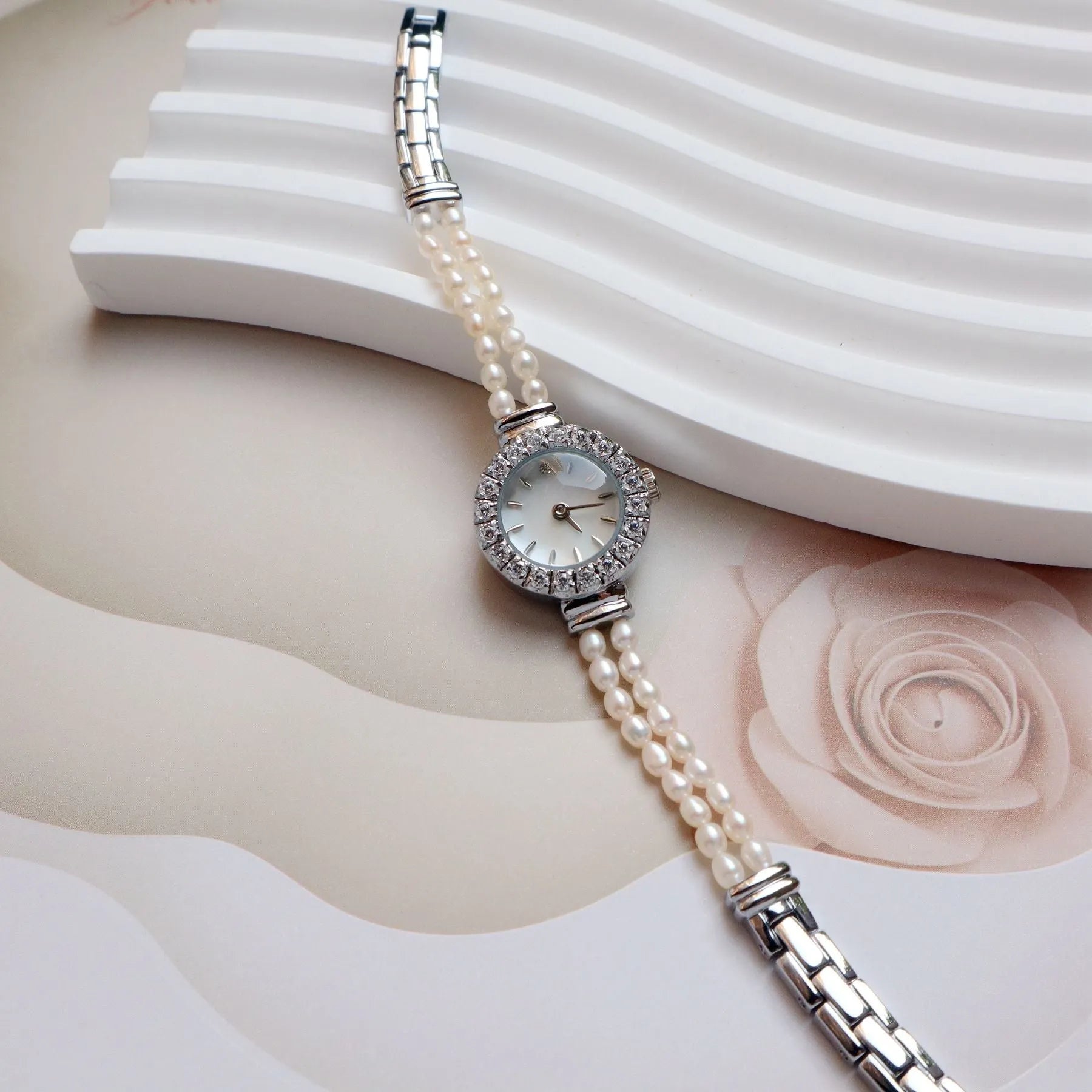 Women's light gold bracelet watch with freshwater pearls on a round 18mm dial.