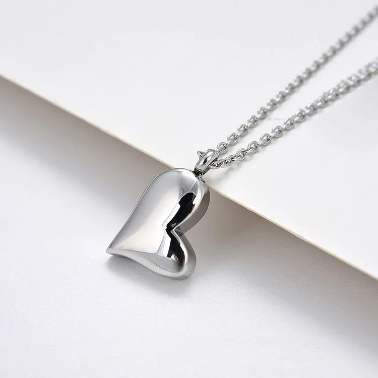 Silver coloured curved peach heart pendant necklace on a stainless steel chain with extension.