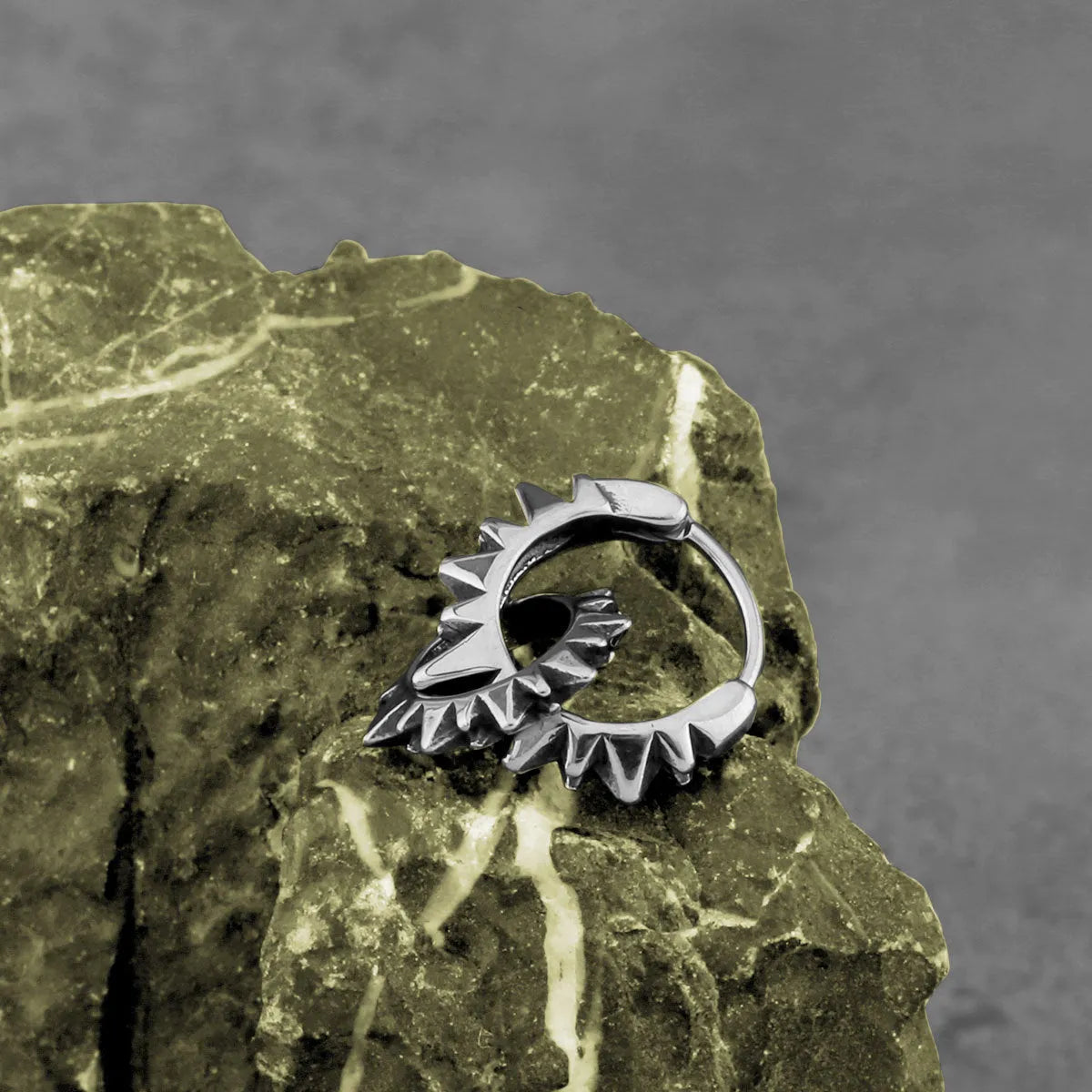 A pair of polished stainless steel round ring earrings in a retro style on a steel colour background.