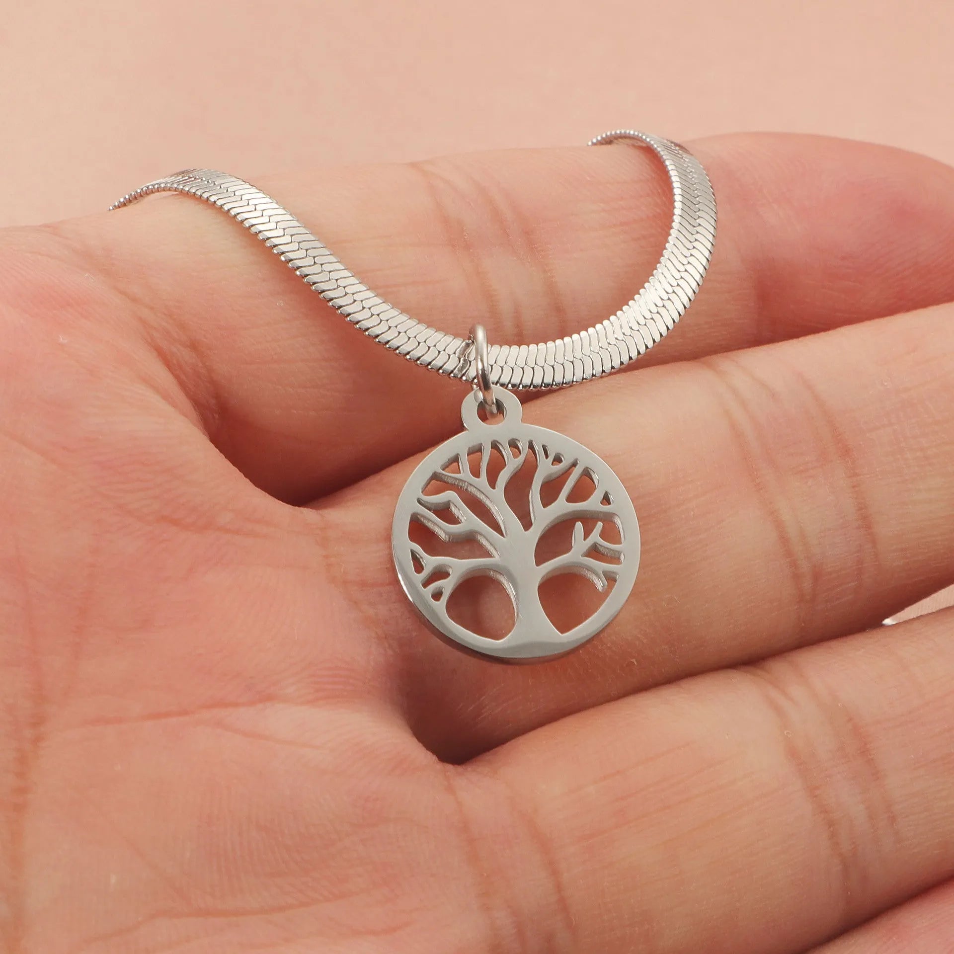 Steel colour tree pendant necklace with a textured snake bones chain on a neutral background.