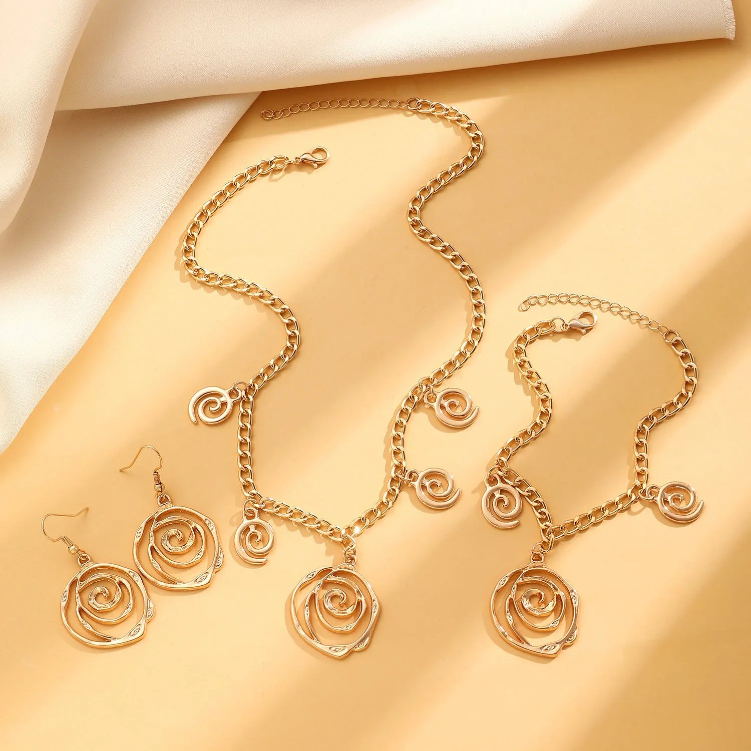 Spiral donut geometric jewellery set with necklace, bracelet, and ear hooks in gold or silver electroplated finish
