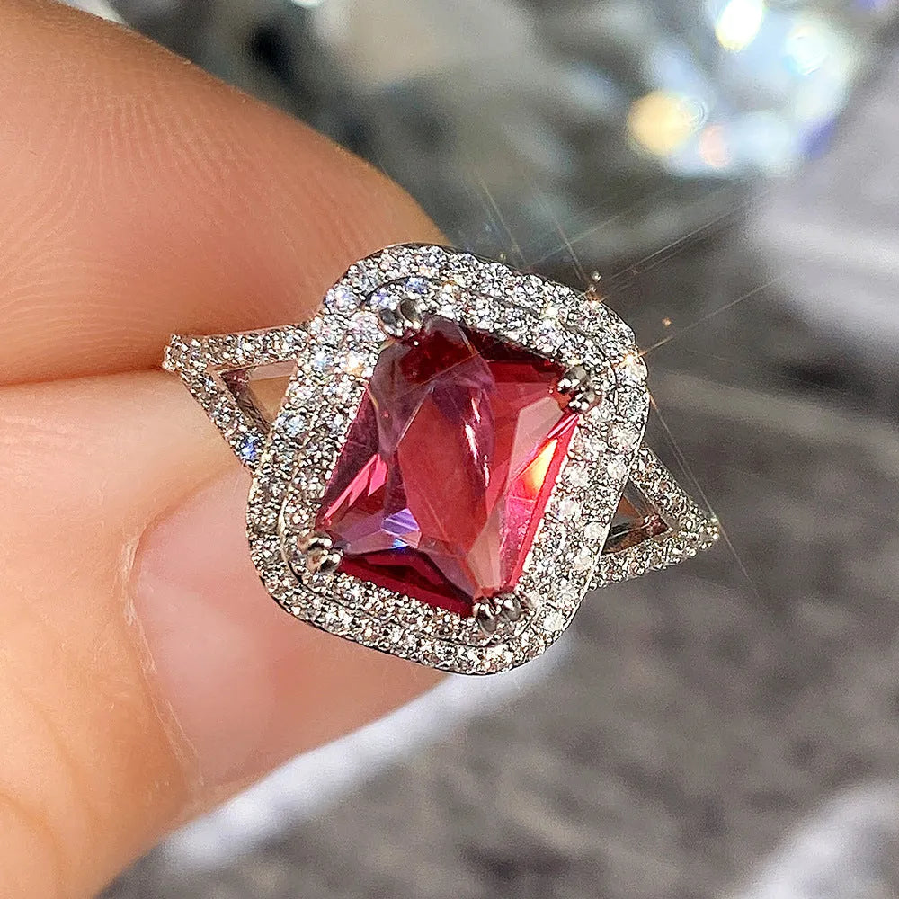 Copper square ring with red rhinestones on a woman's hand, showing geometric design.
