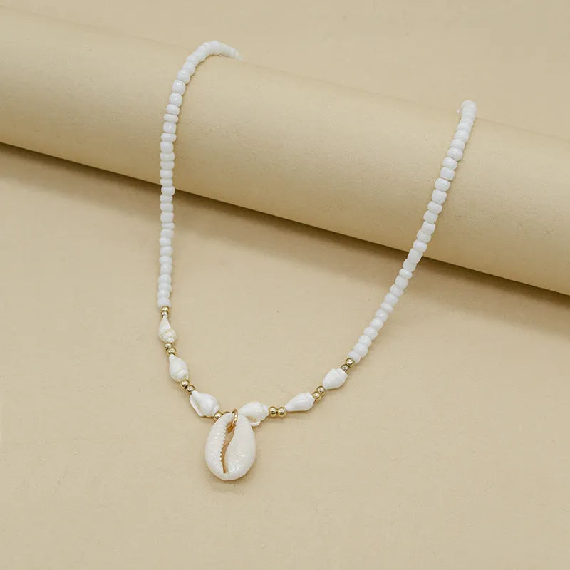 Close-up of a white conch shell necklace pendant made from Mother Pearl on a silver-toned chain.