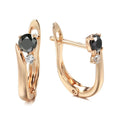 Gold geometric drop earrings with black agate stone inlay on a model's ear