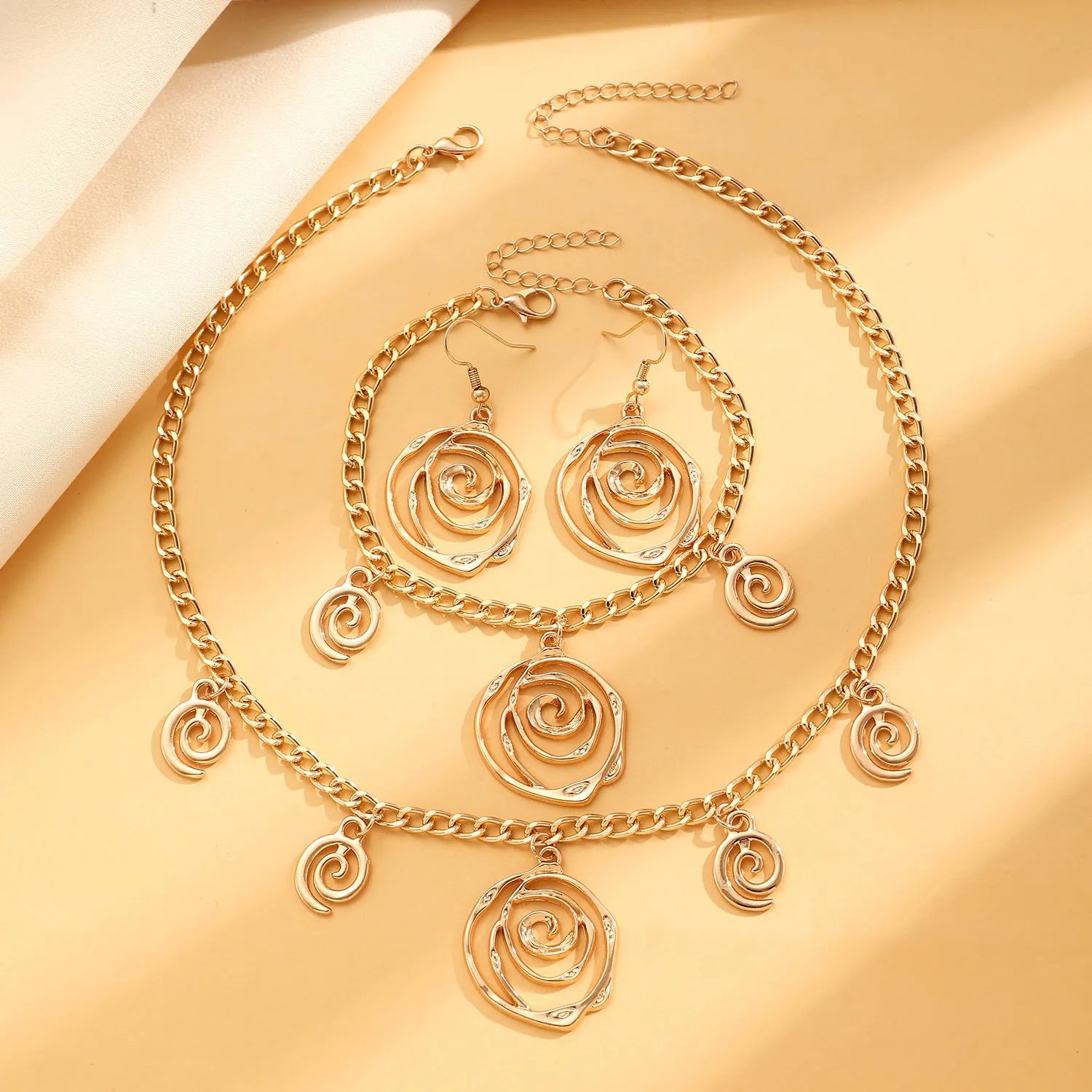 Spiral donut geometric jewellery set with necklace, bracelet, and ear hooks in gold or silver electroplated finish