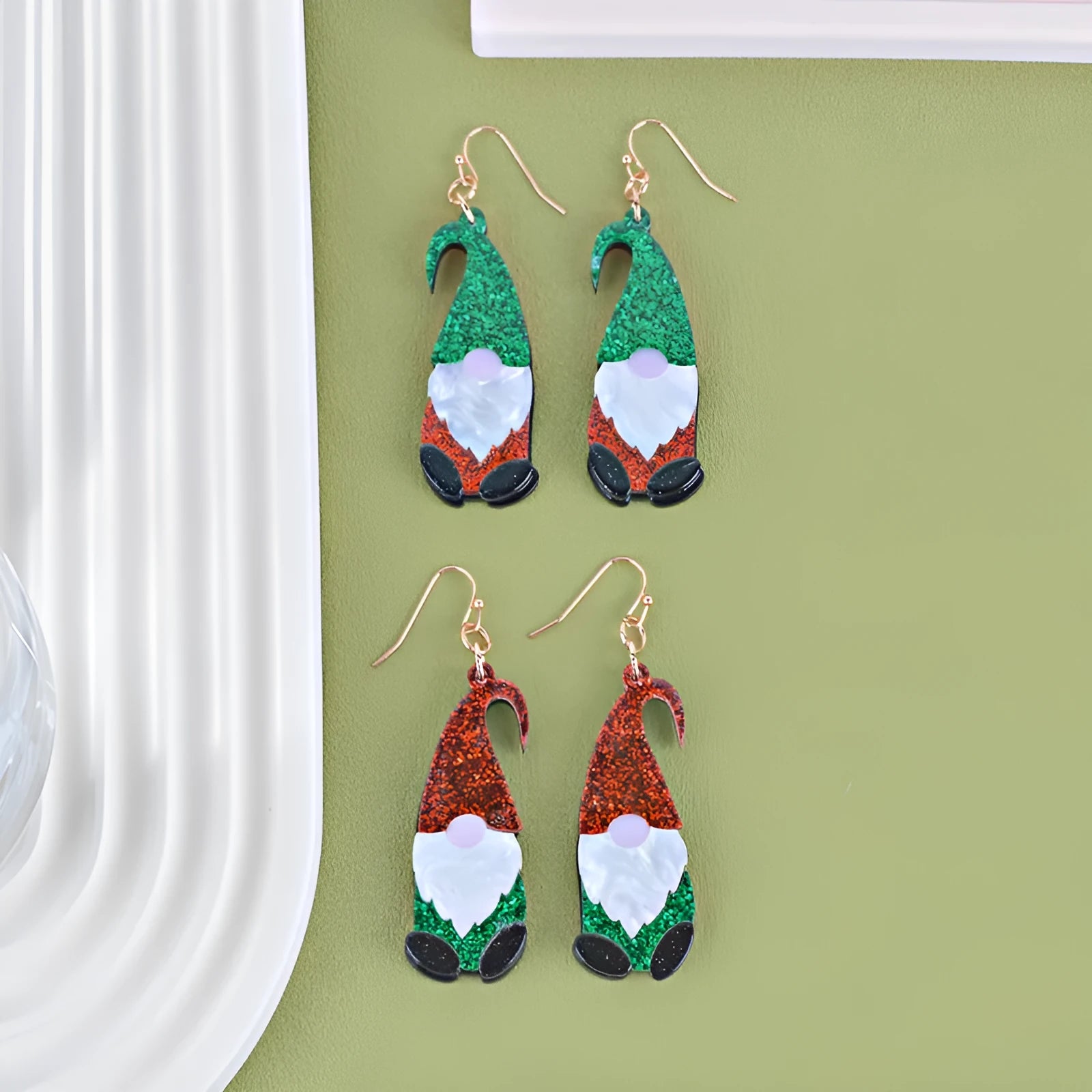 A pair of acrylic earrings shaped like cartoon Santa Claus figures with coloured hats.