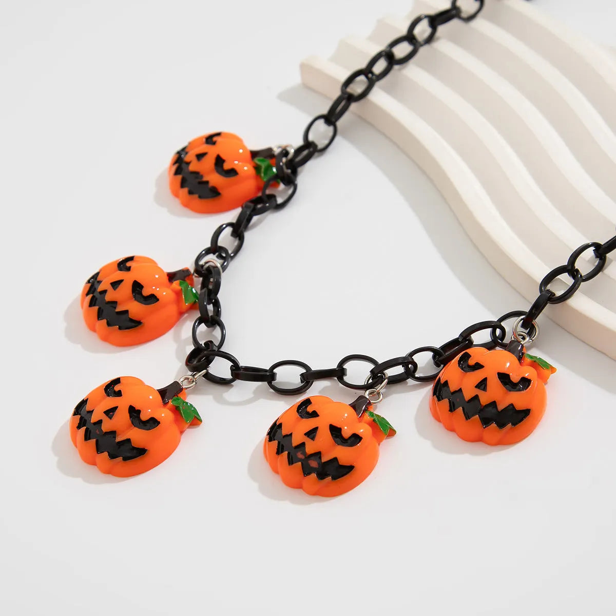 Colourful Halloween necklace showing a cartoon ghost pumpkin pendant on a chain.