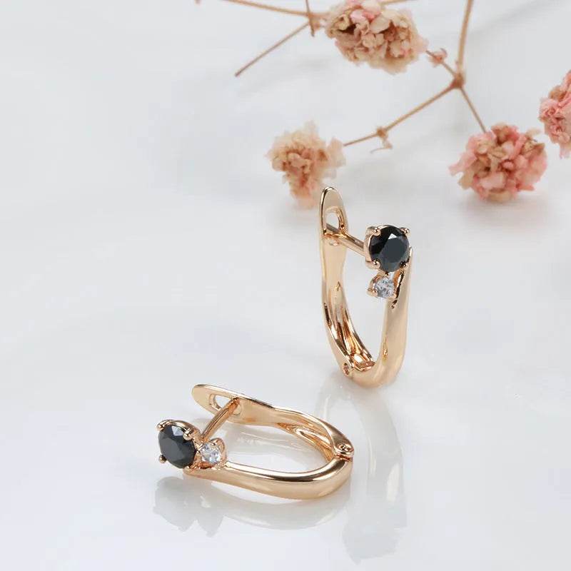 Gold geometric drop earrings with black agate stone inlay on a model's ear