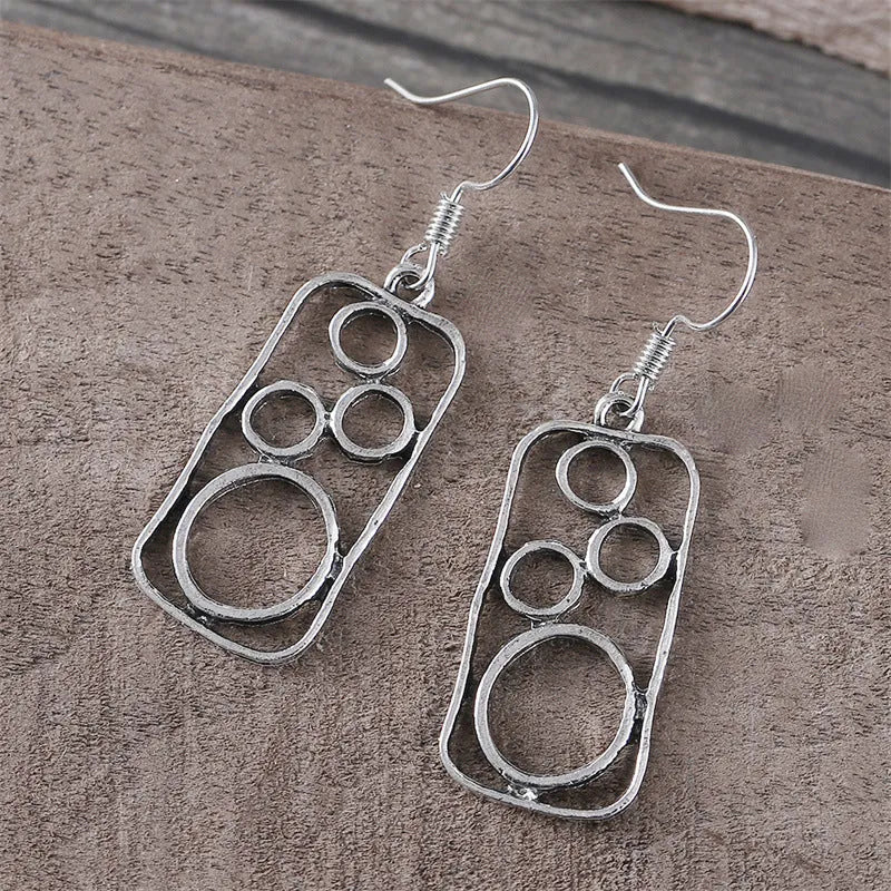 A pair of antique silver geometric earrings showing an irregular square shape inside a round ring.