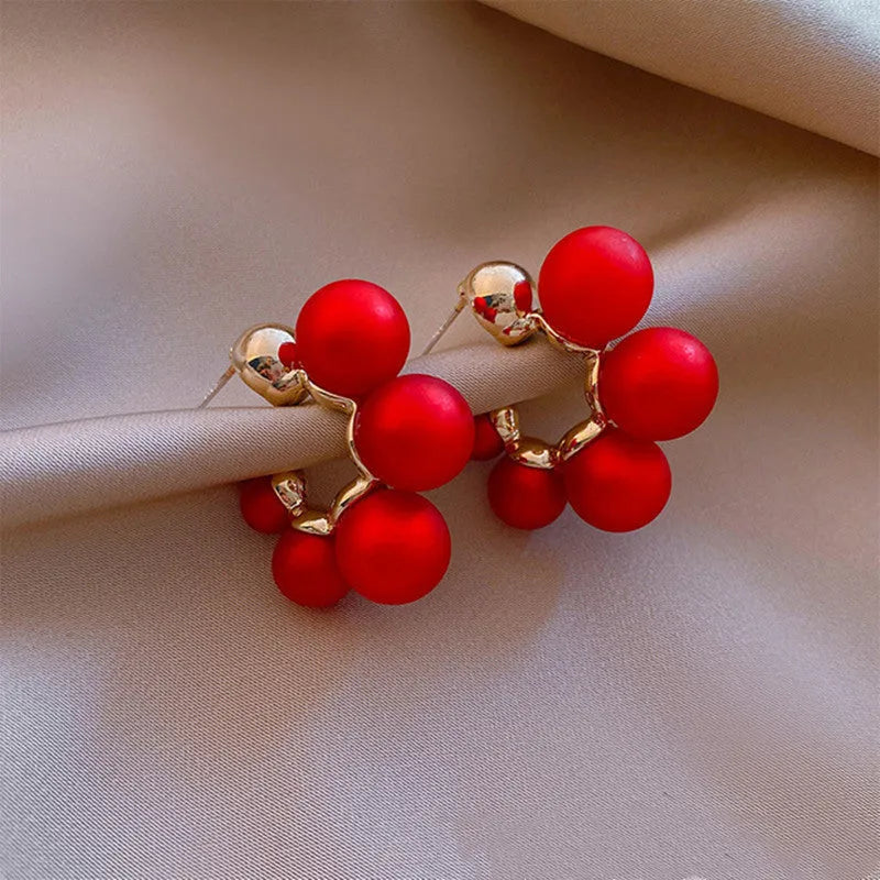 A pair of women's bell-shaped drop earrings in alloy, shown in red and white colour options.