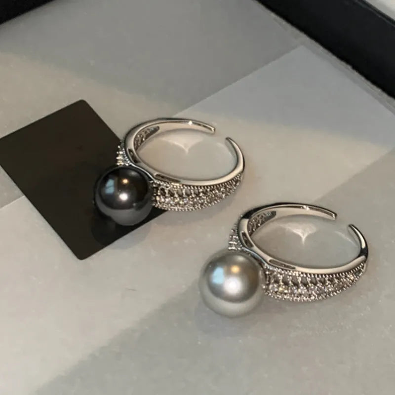 Adjustable geometric copper open finger ring in black pearl colour on grey background