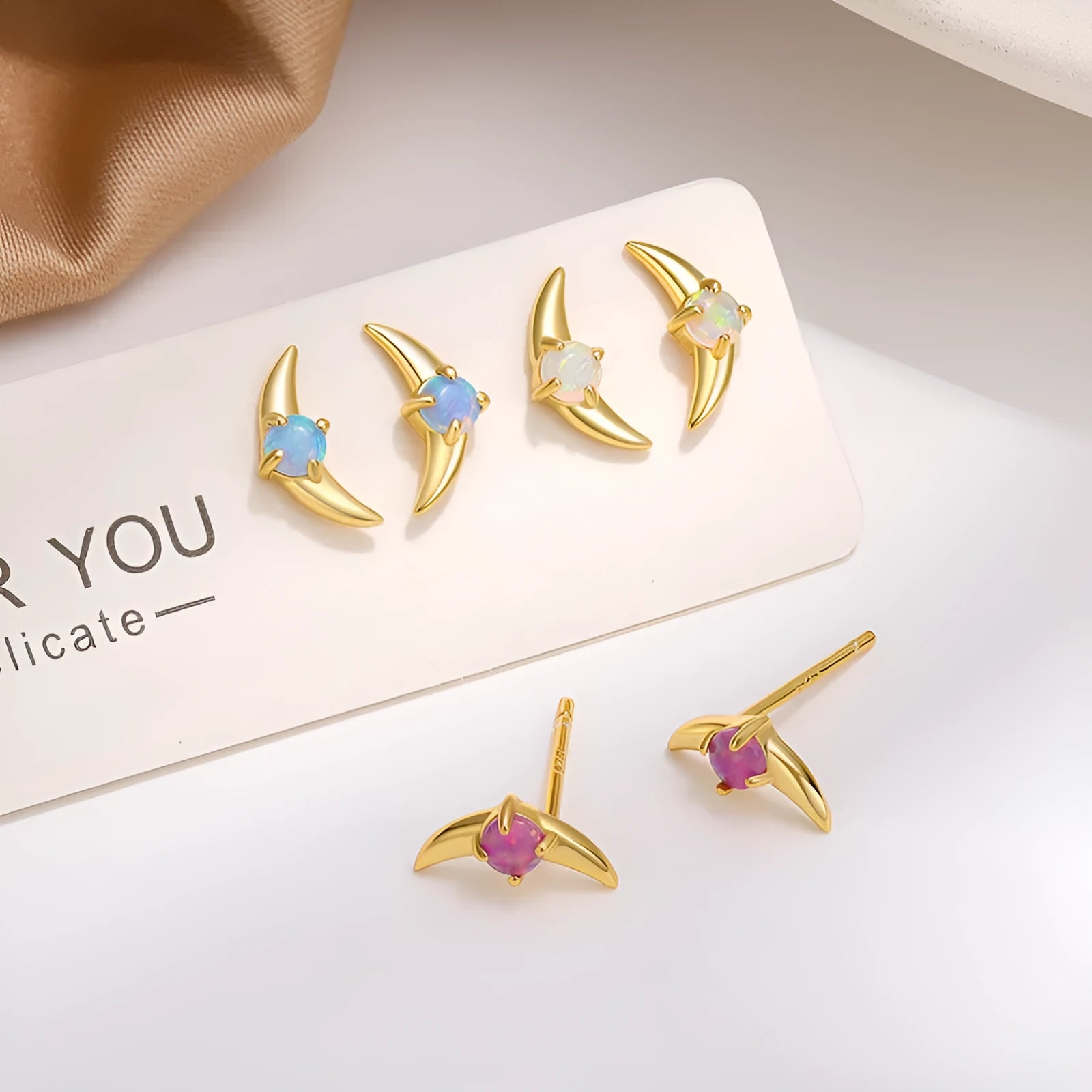 A pair of geometric 925 silver earrings with a stone accent, shown in gold and platinum colour options.