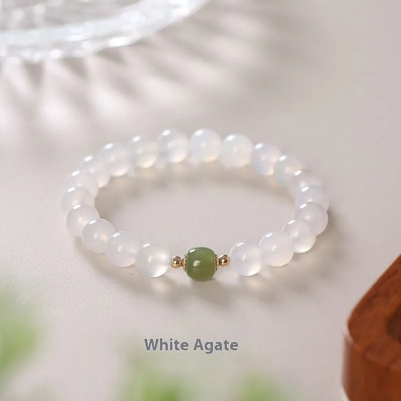 Handmade natural white agate crystal bracelet with cinnabar inlay on wrist, showing 8mm round beads.