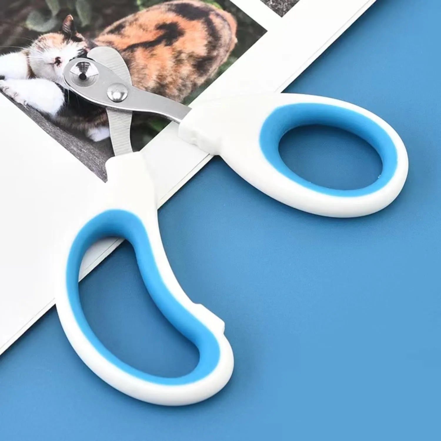 Blue pet nail clippers with circular cutting hole and cushioned handles on a white background