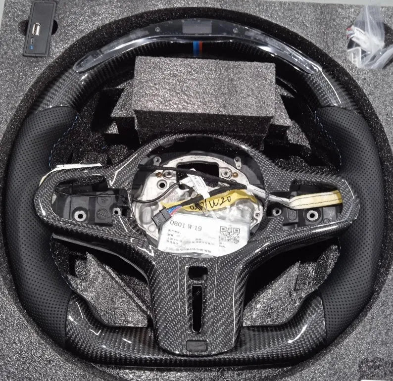 Black carbon fibre sports steering wheel with LED display for BMW X3 and X5 cars.