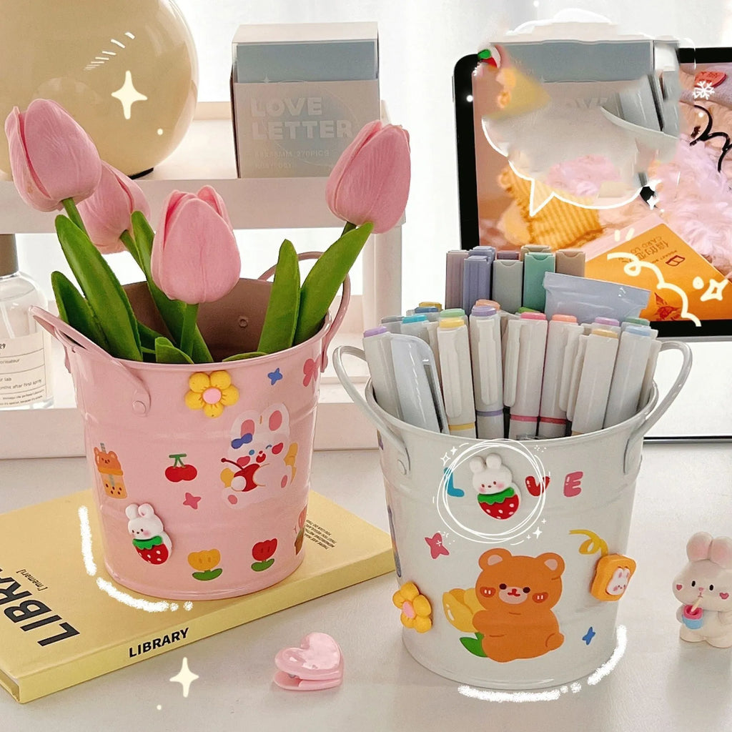 Round metal desk pen holder in a choice of colours, some with decorative sticker patches, for student stationery organisation.