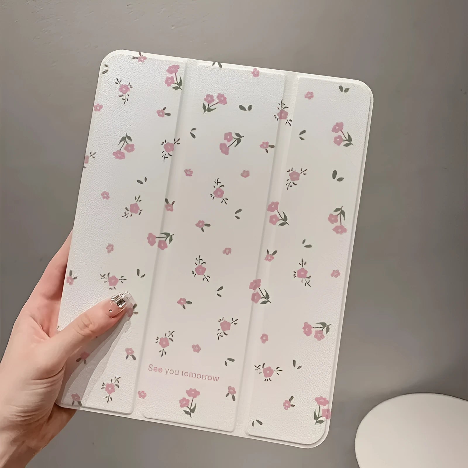Transparent floral patterned tri-fold protective case for Apple iPad in stand position.