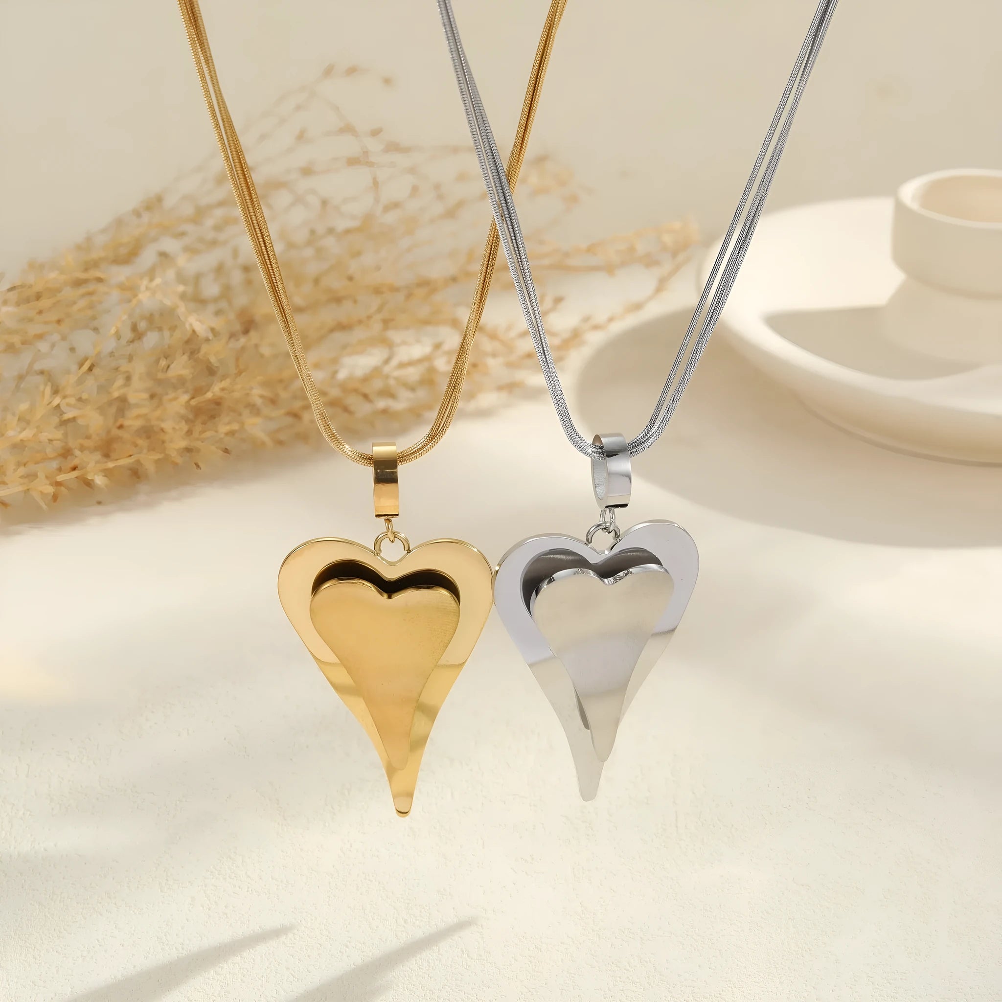 Geometric double heart pendant on a textured snake bones chain necklace in gold or steel finish.