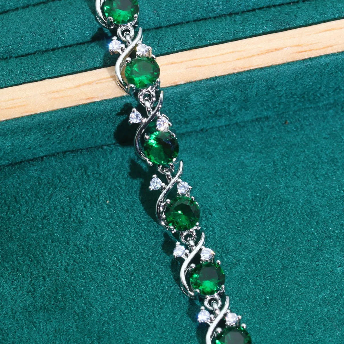 Female model wearing a golden green AAA zircon inlaid copper bracelet with a retro leaf shape design.