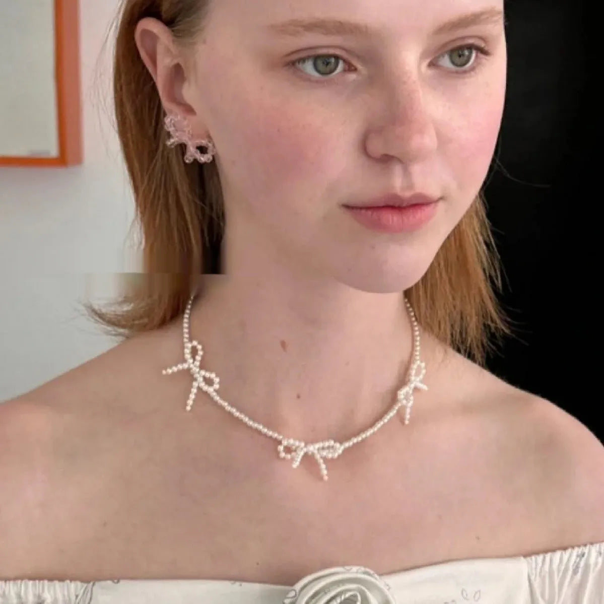 Women's white bow-shaped imitation pearl necklace with an adjustable chain.