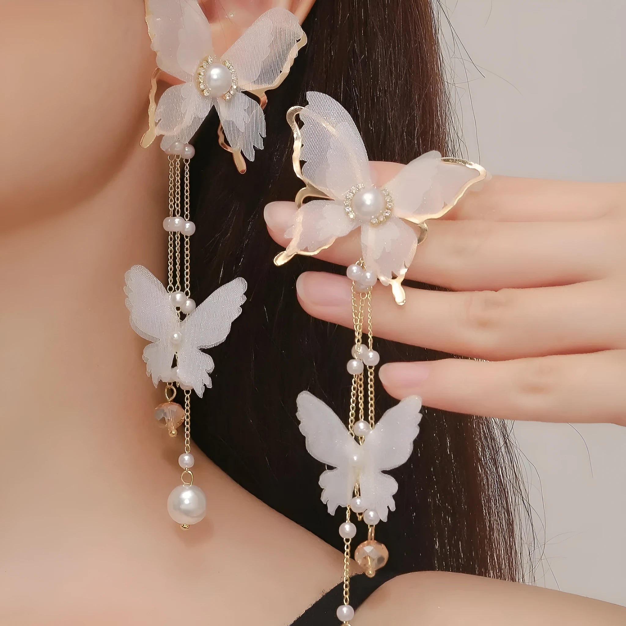 White butterfly earrings with lace detailing, tassels, and rhinestone accents on copper alloy