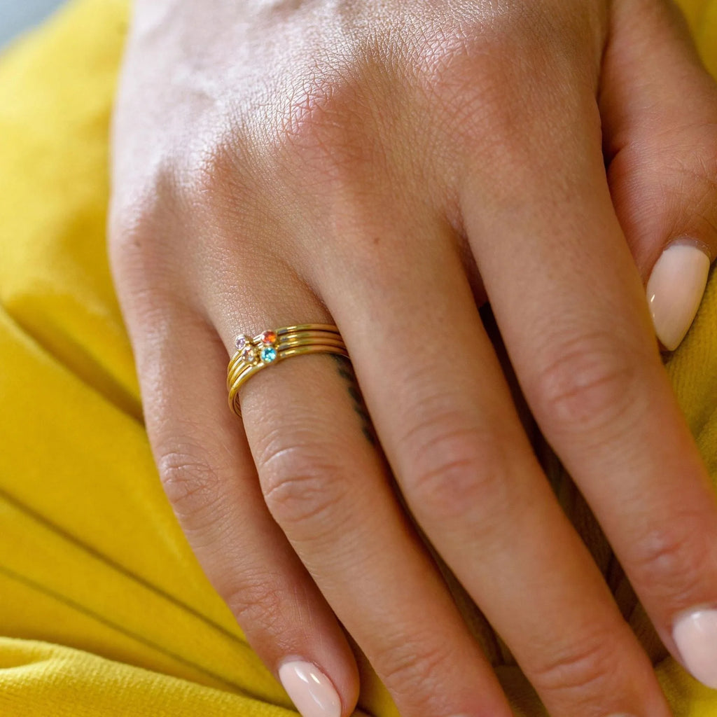 December birthstone geometric engraved ring in titanium steel with gold-coloured handle on a grey background.