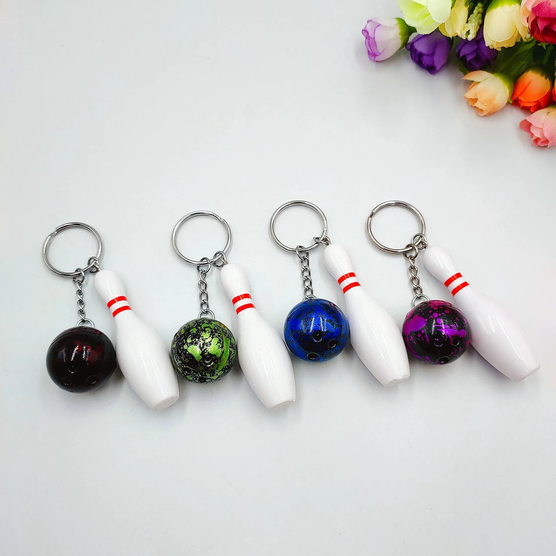 Miniature bowling ball keychain in four colour options: dark red, blue, purple, green