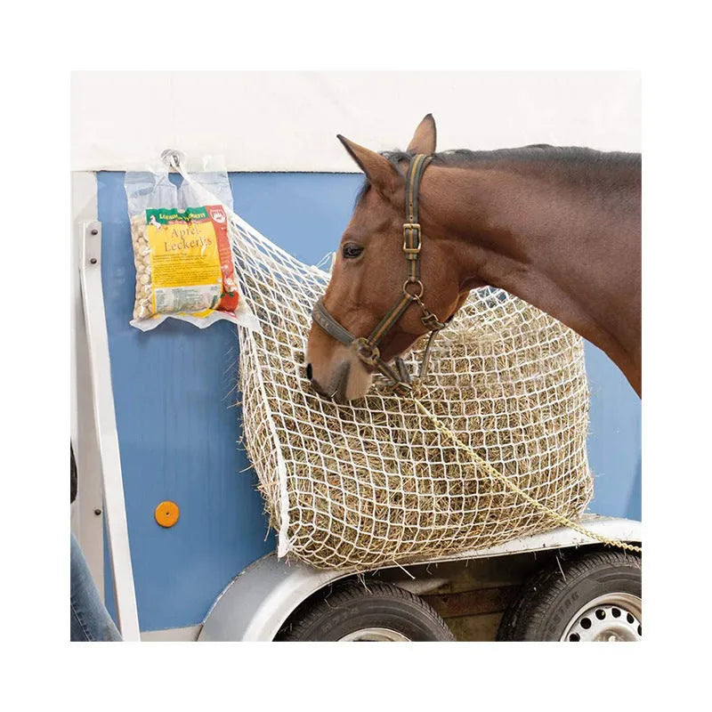 Black woven PE rope grid feeding bag hung on a fence, suitable for horses and cattle.