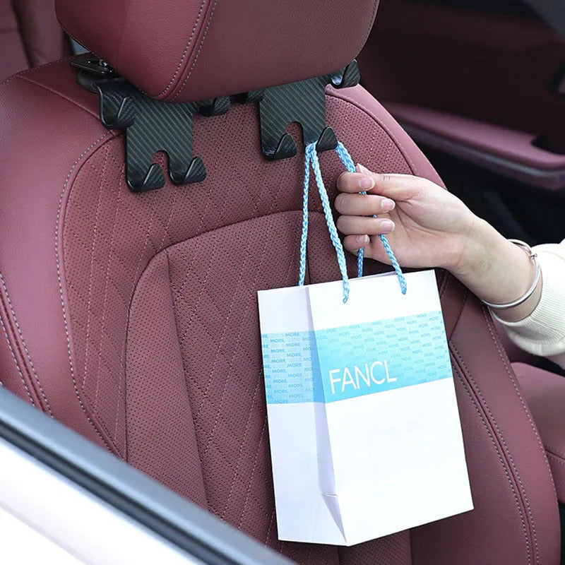 Black ABS car storage hook with carbon fibre pattern, combining a bag hook and mobile phone holder for rear seat installation.