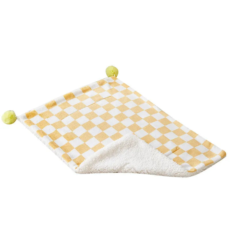 Green plush pet blanket with plaid pattern and fur balls as dog bed mat on sofa