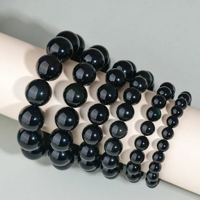 Hand-woven round obsidian bead bracelet for couples, showing colour options on a wrist.