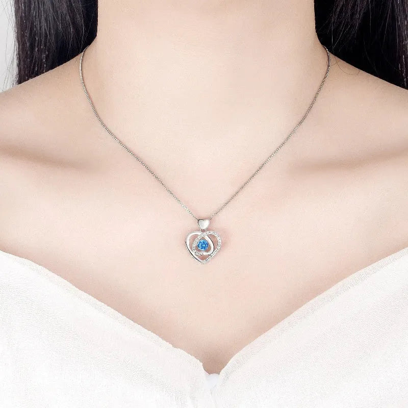 Geometric heart pendant necklace with mixed gem inlays and matching bracelet on blue background
