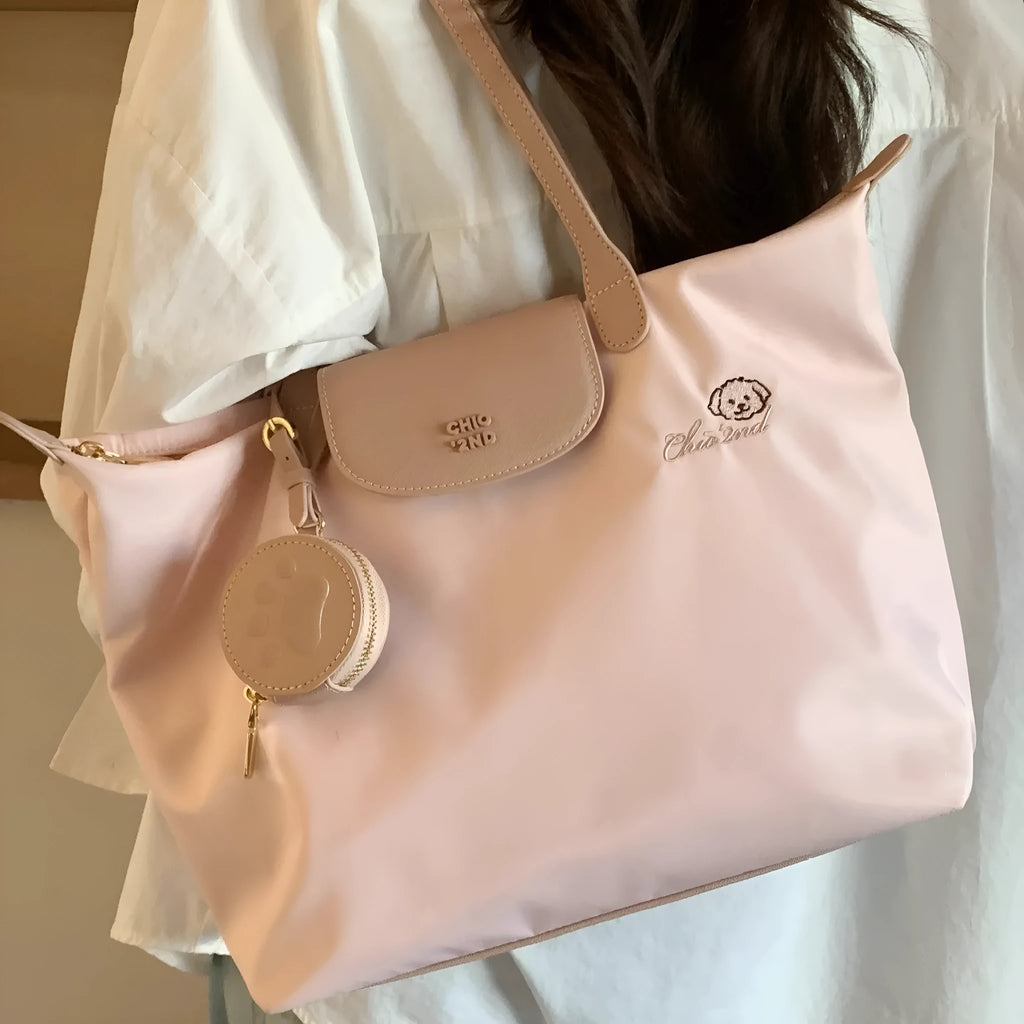 Women's large beige tote shoulder bag with external pockets and a horizontal square shape.