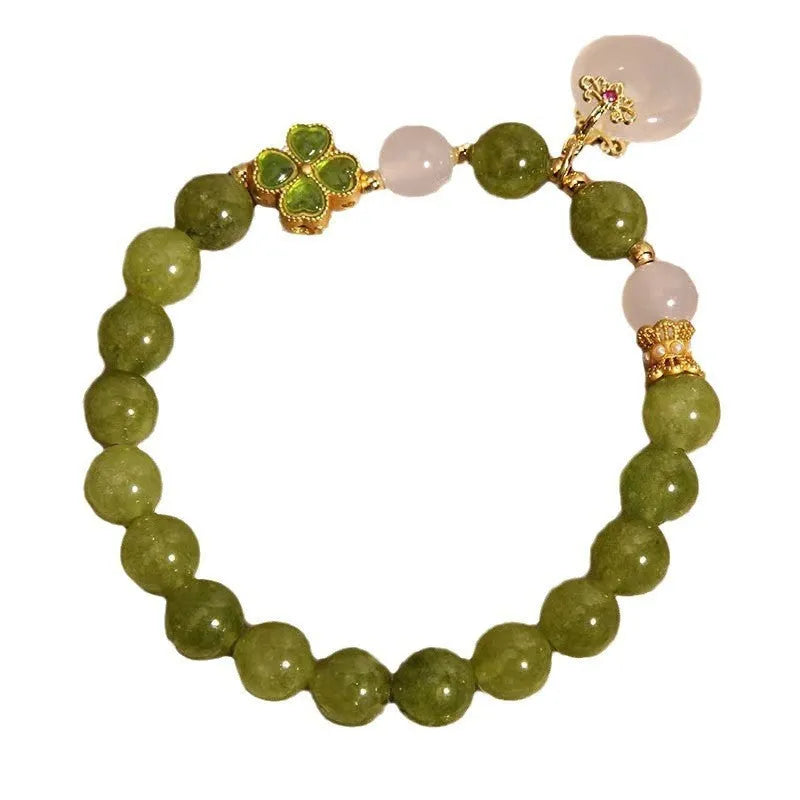 Women's green tourmaline bracelet with four-leaf clover charm and geometric drop pendant on a safety buckle.