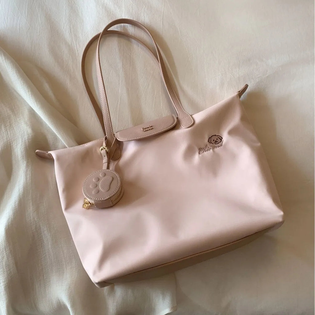 Women's large beige tote shoulder bag with external pockets and a horizontal square shape.