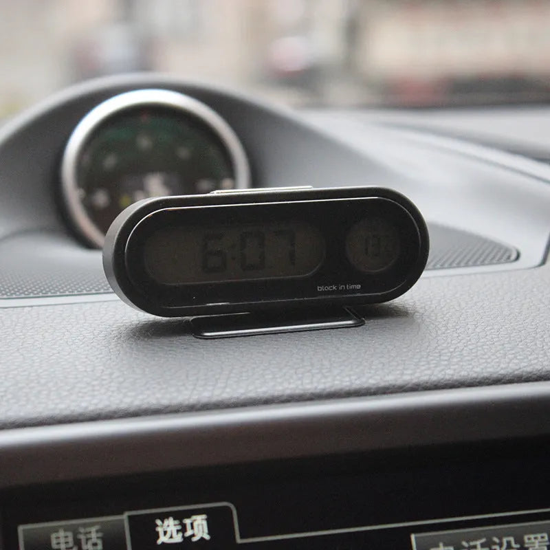 Black electronic car dashboard clock and thermometer unit with digital LED display on an adjustable bracket.