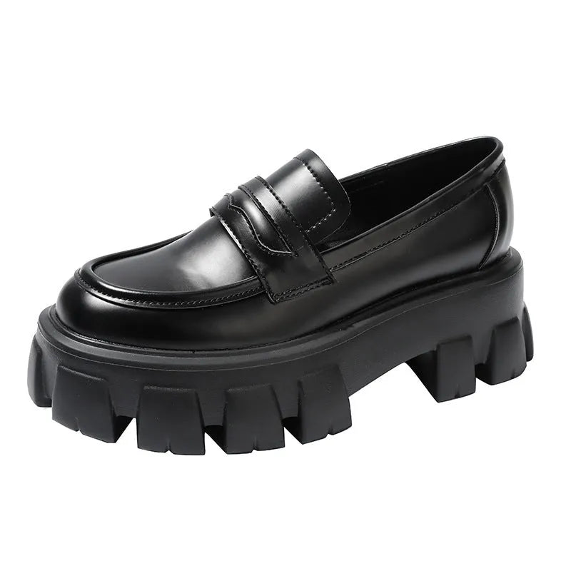 A pair of wide fit patent leather loafers with a rubber sole and muffin heel base.