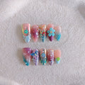Handmade three-dimensional flower and butterfly nail art sculptures in assorted sizes on a manicure set.