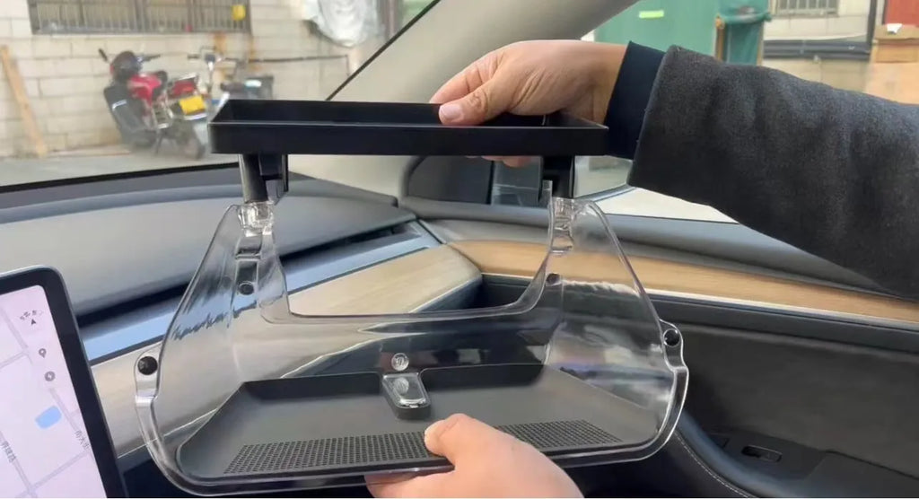 Black ABS plastic storage box installed under the screen of a Tesla Model Y centre console.
