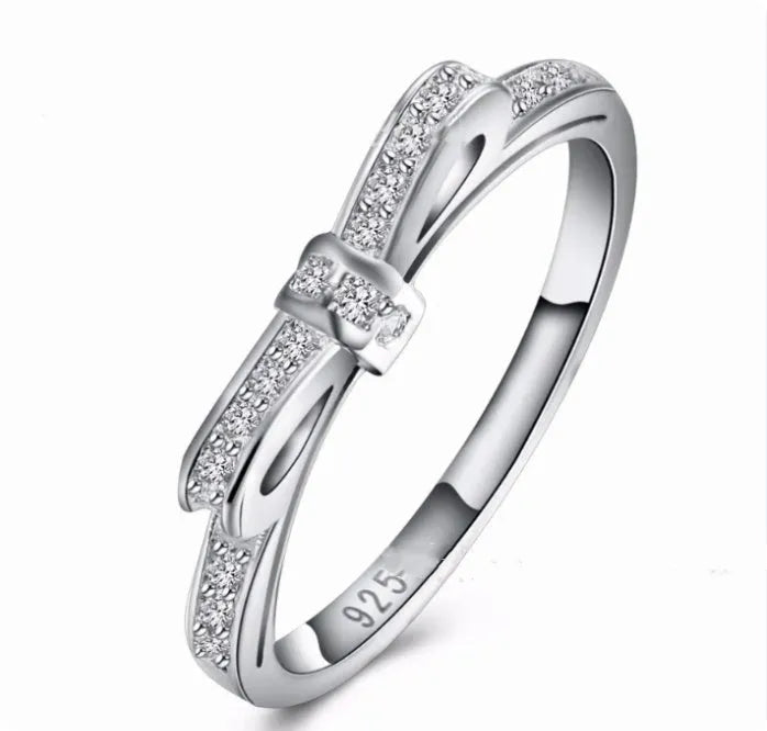 Silver couple style bow ring with rhinestone zircon crystals on finger showing electroplated finish