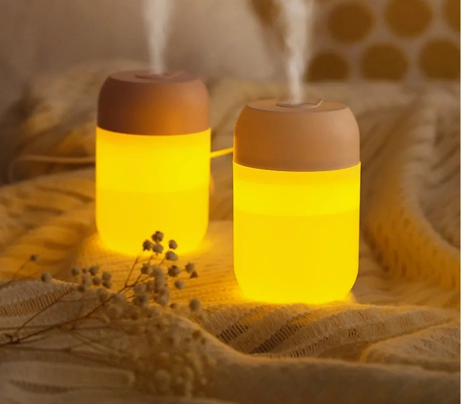White cylindrical mini USB humidifier with aromatherapy function on a wooden surface.