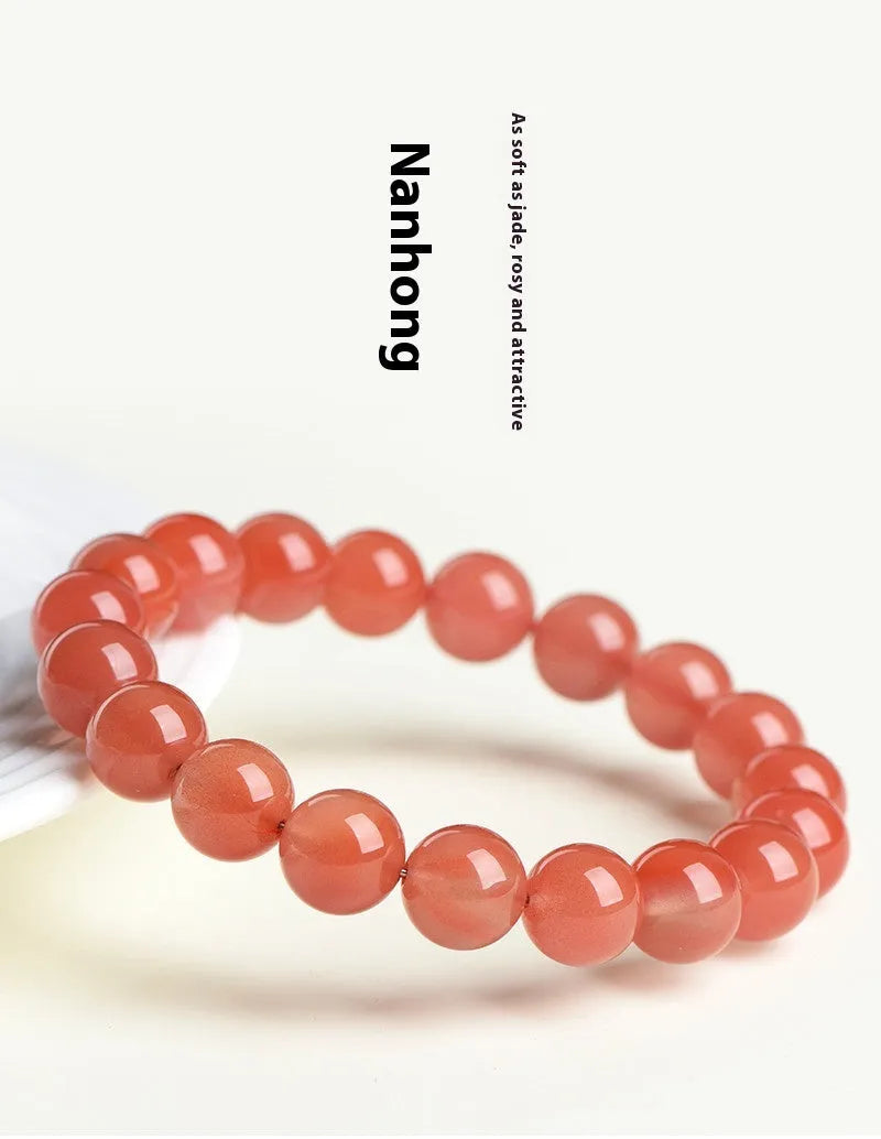 Natural cherry red agate bead bracelet on a wrist, showing polished stones and string construction.