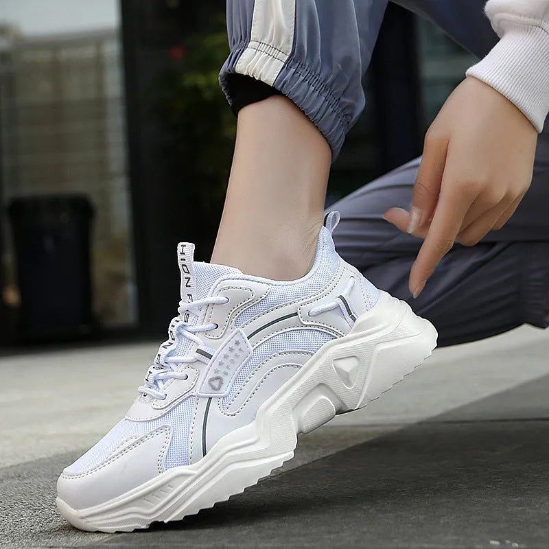 Women's white thick-soled casual sneakers with mesh upper, round toe, and buckle detail.
