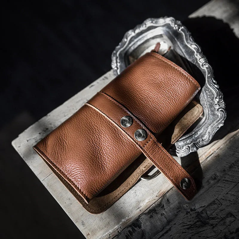 Handmade solid colour cow leather vintage wallet with tape closure, shown in black and dark brown.