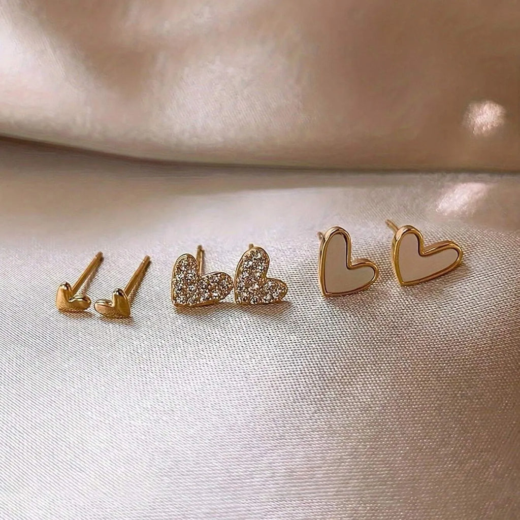 Set of three pairs of heart-shaped alloy earrings in gold, black, black and white, and pink colours.