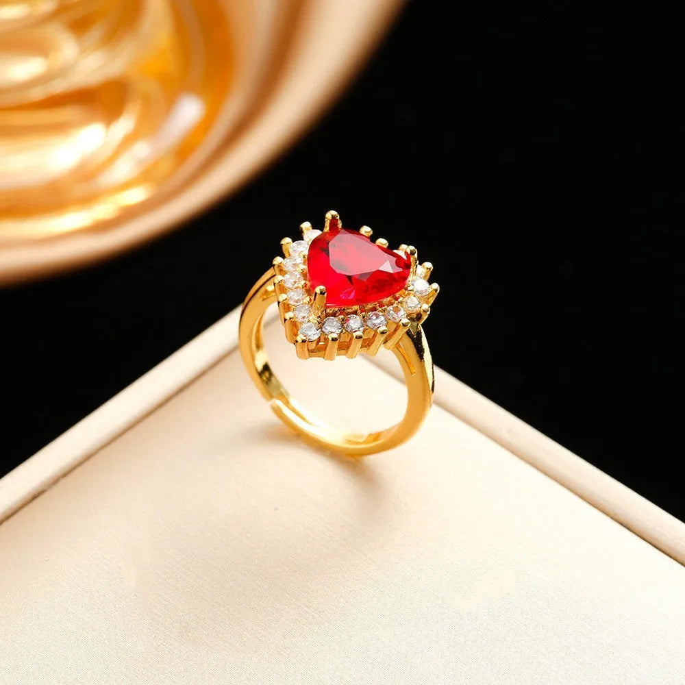 Gold red titanium steel jewellery set with heart and flower pendant necklace, matching stud earrings, and ring on a plain background.