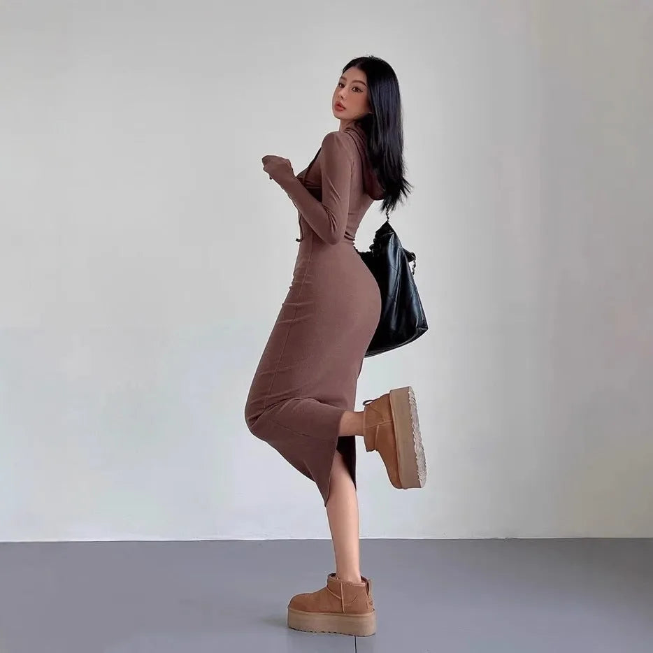 A woman wearing a grey hooded sheath dress with long sleeves and an over-the-knee length.