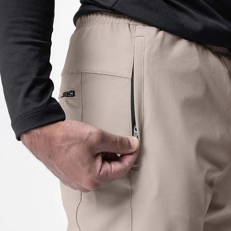 Man wearing dark grey loose-fit ankle-tied running pants made from quick-drying polyester fabric.